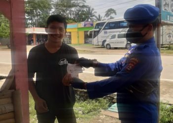 Di Pesisir Sumur, Personel Ditpolairud Polda Banten Bagikan Ratusan Masker