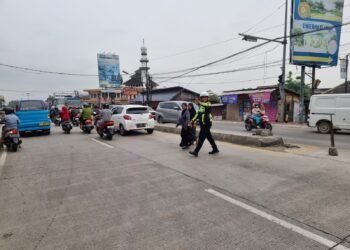Anggota lalu lintas polsek kramatwatu Polresta Serkot membantu menyebrangkan masyarakat