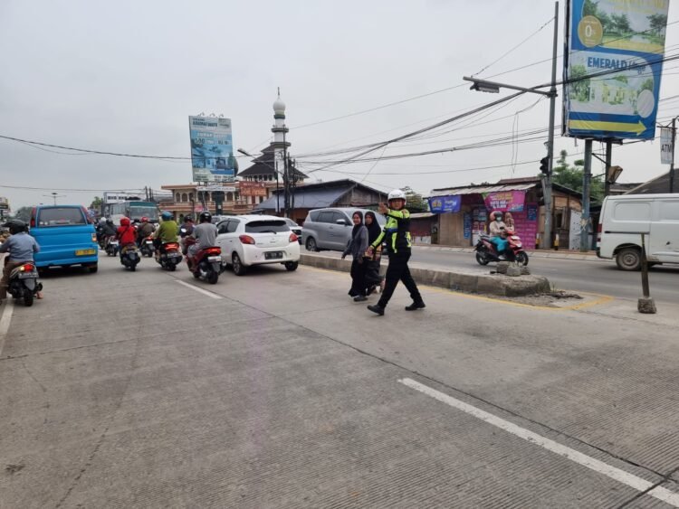 Anggota lalu lintas polsek kramatwatu Polresta Serkot membantu menyebrangkan masyarakat